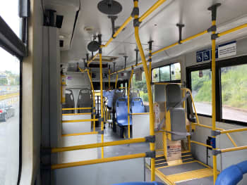 Interior de un bus padrón del SITME sin pasajeros. Se pueden apreeeciar los pasamanos contrastantes y el elevador para sillas de ruedas tipo asiento, el cual utiliza una puerta completa.